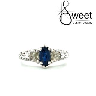 14KT WHITE GOLD ENGAGEMENT RING FEATURING ONE MARQUISE SHAPED BLUE SAPPHIRE 7X4MM ACCENTED BY TWO TRILLION SHAPED DIAMONDS