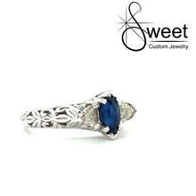 Load image into Gallery viewer, 14KT WHITE GOLD ENGAGEMENT RING FEATURING ONE MARQUISE SHAPED BLUE SAPPHIRE 7X4MM ACCENTED BY TWO TRILLION SHAPED DIAMONDS