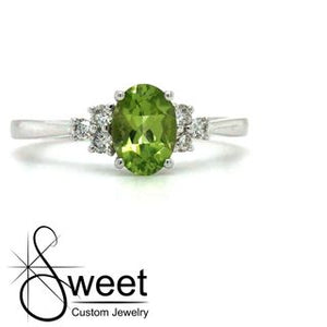 14KT WHITE GOLD RING FEATURING ONE OVAL SHAPED GENUINE PERIDOT ACCENTED BY 3 ROUND BRILLIANT CUT DIAMONDS .15CTTW