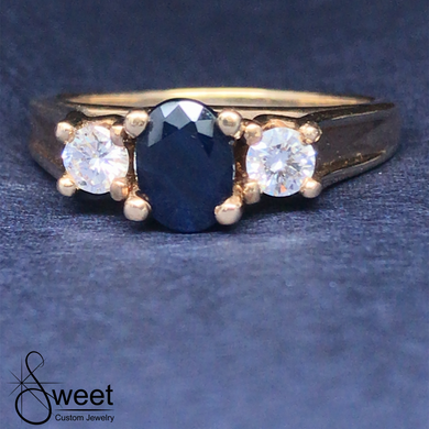 14kt YELLOW GOLD THREE STONE RING FEATURING ONE GENUINE BLUE SAPPHIRE